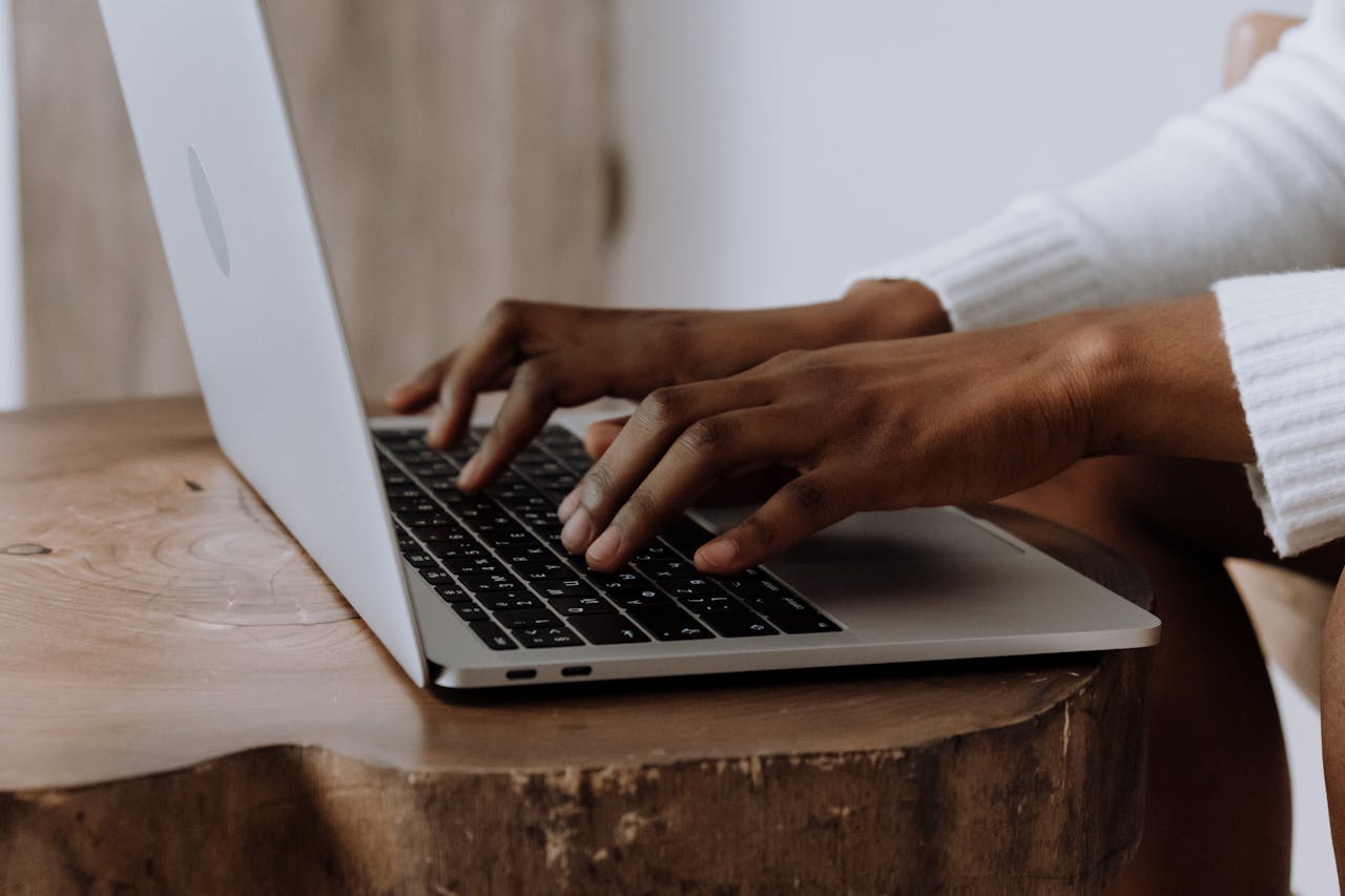 our-experience Hands typing on a laptop in a cozy indoor setting, focusing on technology and digital work.